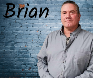 Finger Lakes Independence Center Ramp Specialist Brian Yonkin in front of a grey brick wall with first name in black letters