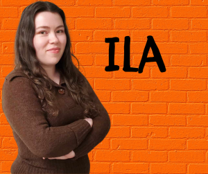 Finger Lakes Independence Center Employment Advocate Ila Rose (she, her) in front of a orange brick wall with first name in black letters