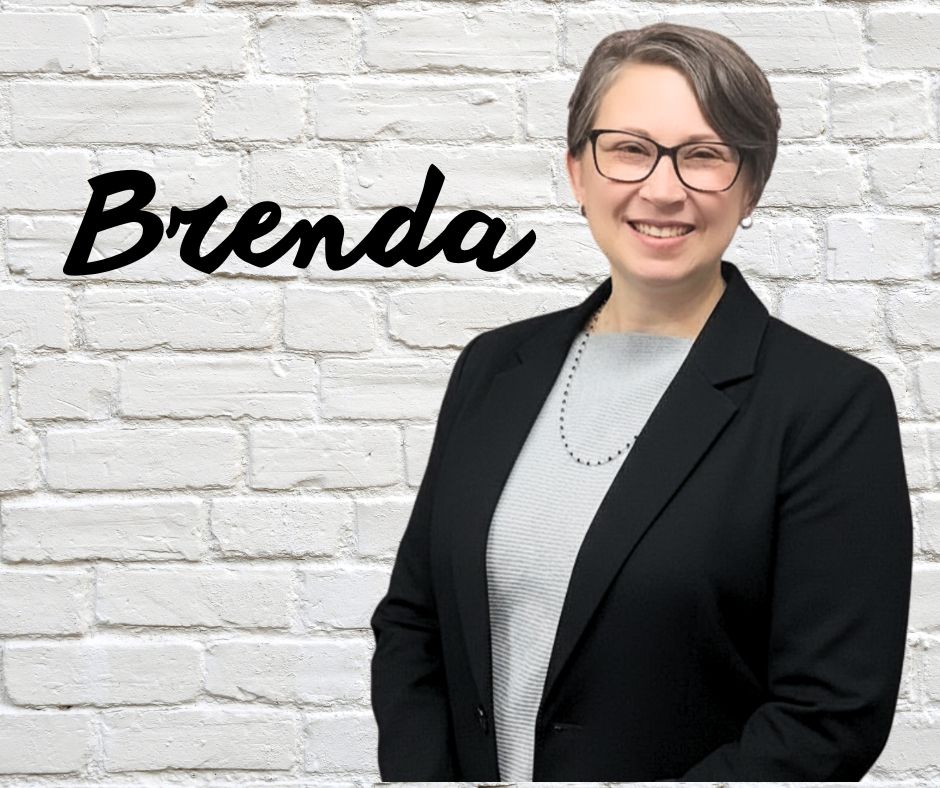 Finger Lakes Independence Center Brenda Pepe in front of a white brick wall with first name in black letters